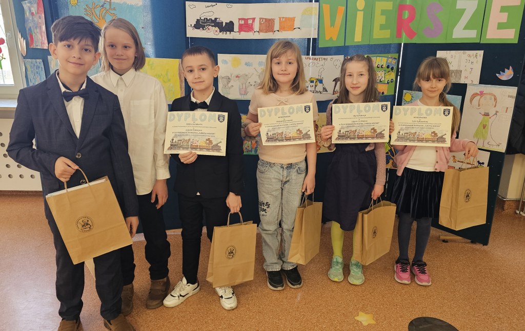 Uczniowie prezentują dyplomy i nagrody zdobyte w Konkursie Dzielnicowym ,,Lubimy wiersze".